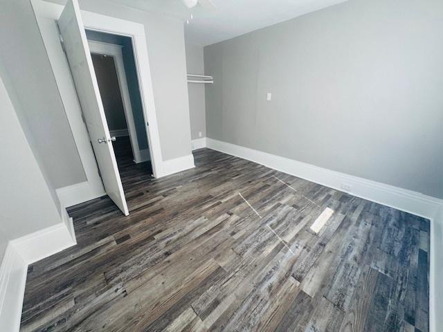 unfurnished bedroom with a ceiling fan, baseboards, and dark wood-style flooring