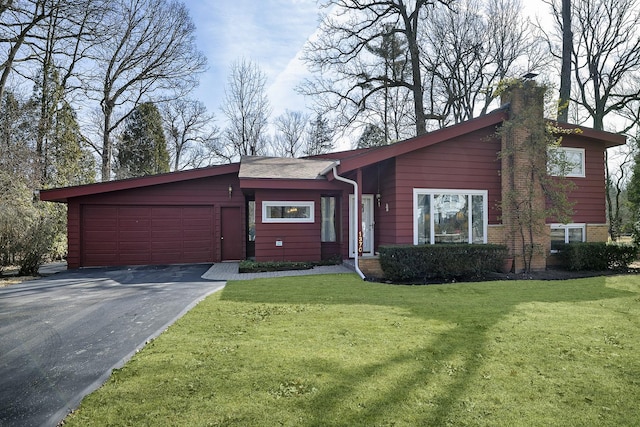 view of front facade with a front yard, an attached garage, driveway, and a chimney