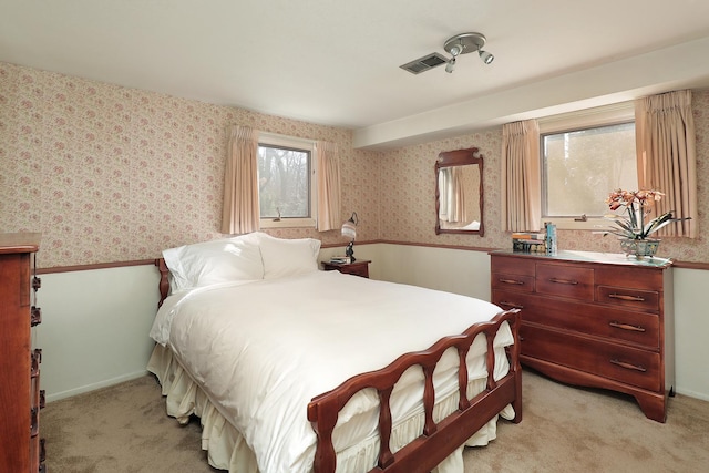 bedroom with wallpapered walls, light colored carpet, visible vents, and baseboards