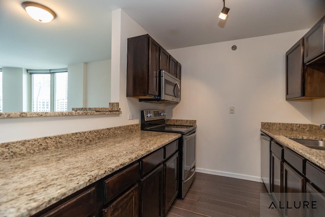 kitchen with a sink, dark wood finished floors, stainless steel appliances, dark brown cabinetry, and baseboards