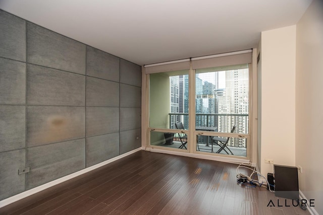 empty room featuring dark wood-style floors, a city view, and floor to ceiling windows