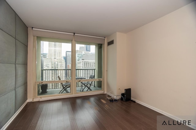 spare room with dark wood finished floors, a view of city, baseboards, and visible vents