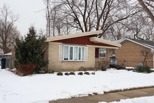 view of snow covered exterior featuring board and batten siding and brick siding