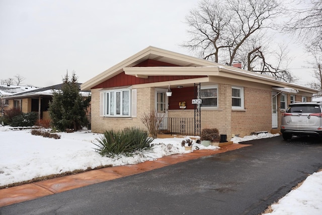 bungalow with aphalt driveway, brick siding, and a chimney