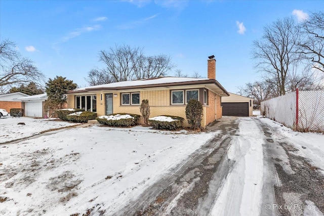 view of front of property with a detached garage, fence, an outdoor structure, brick siding, and a chimney