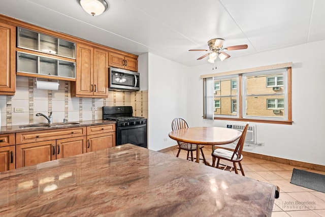 kitchen featuring a sink, black range with gas stovetop, stainless steel microwave, tile patterned floors, and backsplash