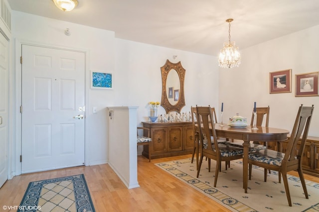 dining room featuring a notable chandelier, light wood-type flooring, and baseboards