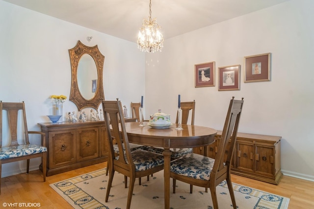 dining area featuring light wood-style floors, baseboards, and a chandelier