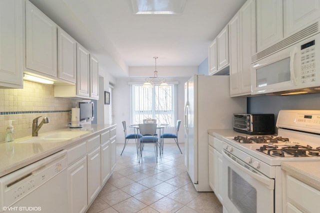 kitchen featuring white cabinets, white appliances, light countertops, and a sink