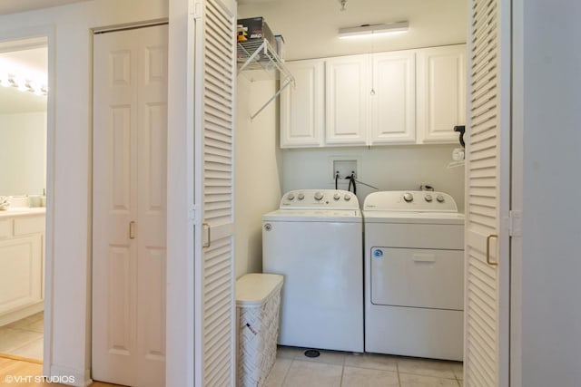 laundry area with washer and dryer, light tile patterned floors, and cabinet space