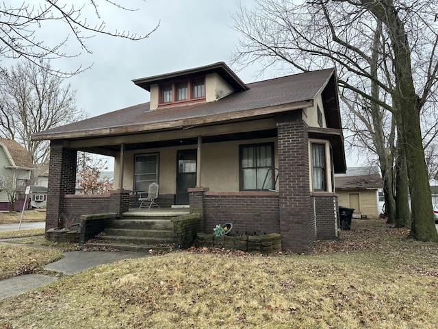 bungalow featuring stucco siding, brick siding, and covered porch