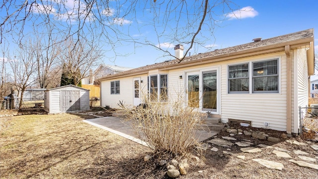 back of property with entry steps, fence, a storage shed, an outdoor structure, and a chimney