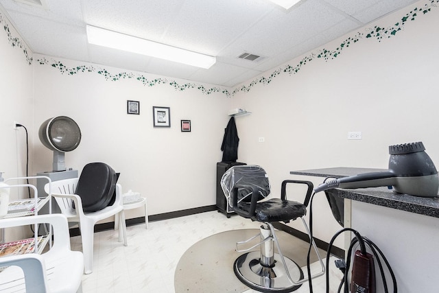 interior space featuring a drop ceiling, visible vents, baseboards, and marble finish floor