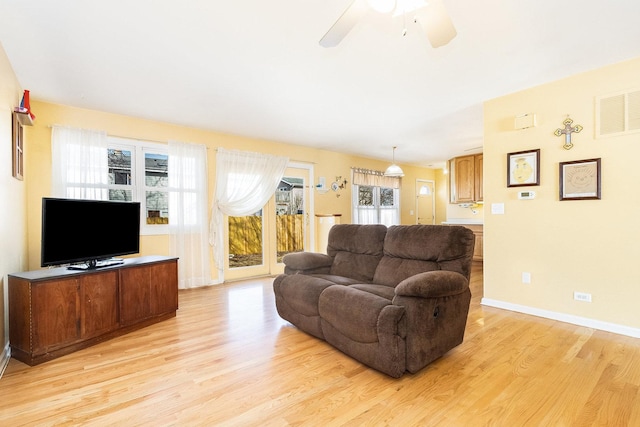 living room featuring light wood-type flooring, baseboards, visible vents, and ceiling fan