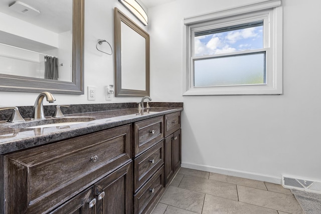 full bathroom featuring visible vents, baseboards, double vanity, tile patterned floors, and a sink