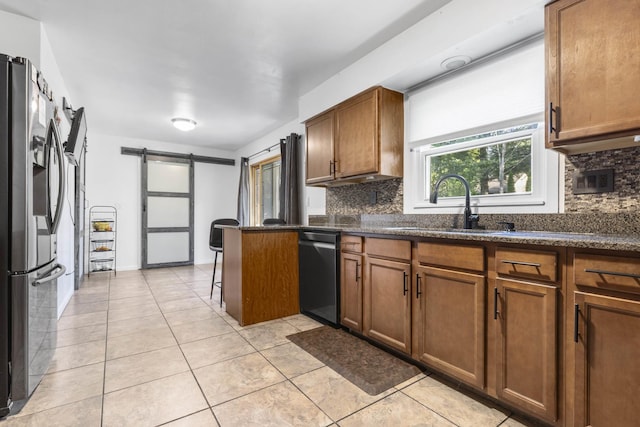 kitchen with light tile patterned floors, backsplash, stainless steel appliances, and a barn door