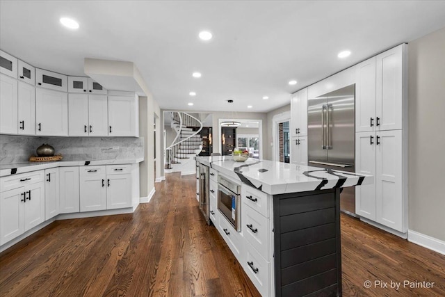 kitchen featuring decorative backsplash, built in appliances, dark wood-style floors, and white cabinets