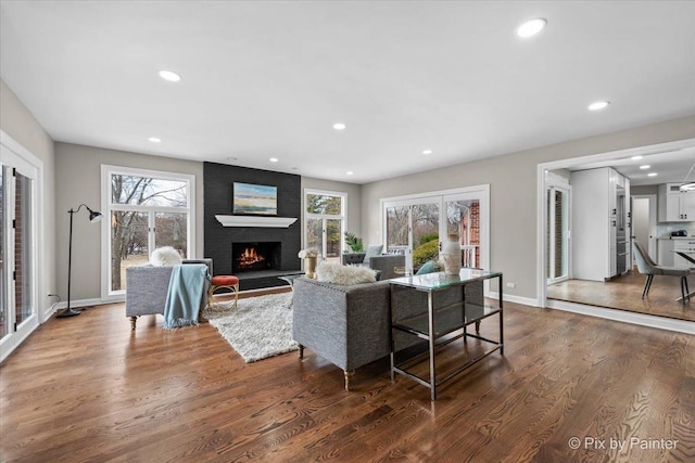 living room with dark wood-style floors, recessed lighting, a healthy amount of sunlight, and a fireplace