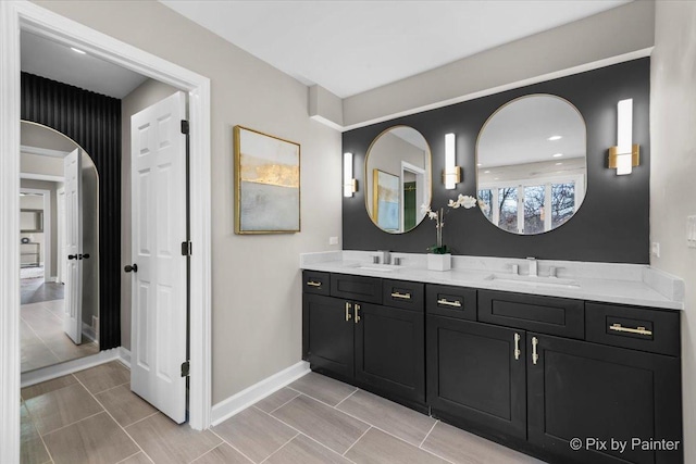 full bath featuring a sink, baseboards, and double vanity