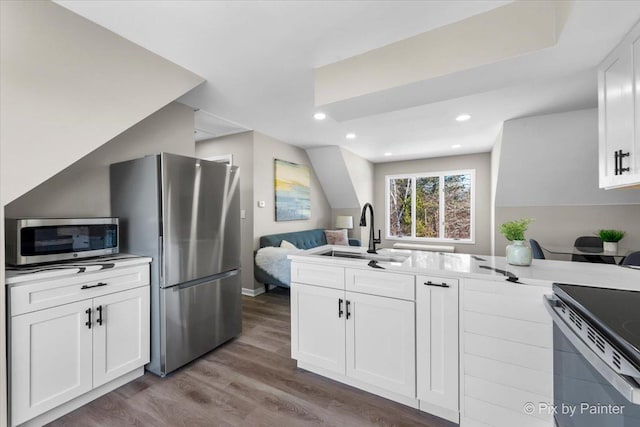 kitchen with white cabinets, wood finished floors, appliances with stainless steel finishes, and a sink