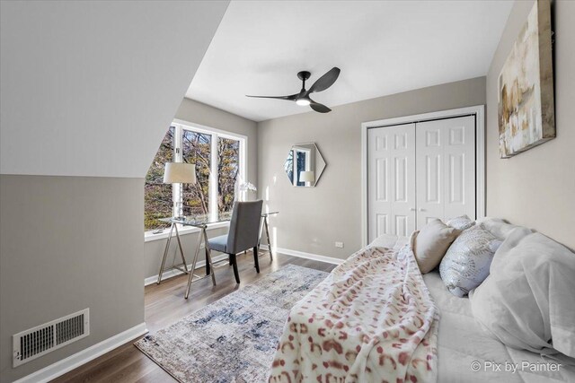 bedroom with visible vents, a ceiling fan, wood finished floors, a closet, and baseboards