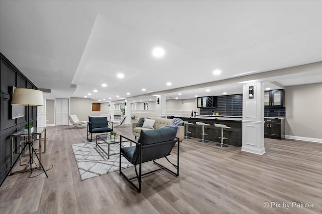 living room with wet bar, recessed lighting, light wood-style floors, and baseboards