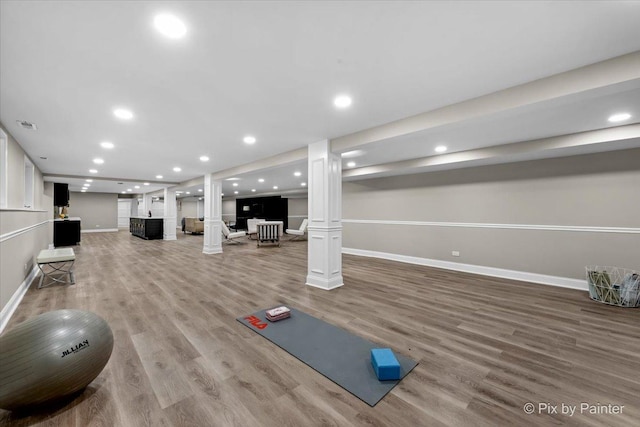 exercise area featuring recessed lighting, light wood-style flooring, baseboards, and ornate columns