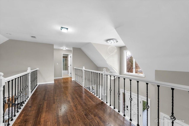 hall with wood finished floors, visible vents, baseboards, an inviting chandelier, and vaulted ceiling