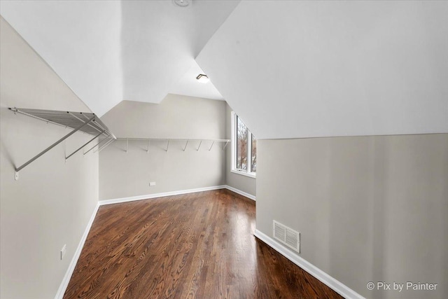 additional living space featuring visible vents, lofted ceiling, baseboards, and wood finished floors