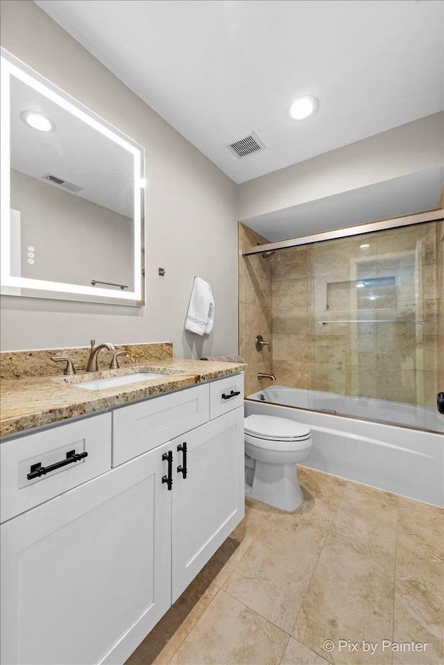 full bathroom with visible vents, toilet, vanity, and bath / shower combo with glass door