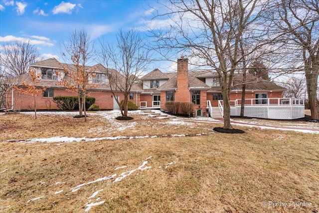 rear view of property featuring brick siding, a lawn, and a chimney