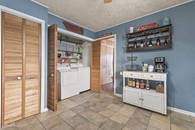 clothes washing area with independent washer and dryer, a textured ceiling, light tile patterned flooring, baseboards, and laundry area