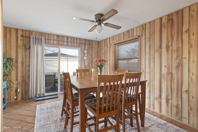 tiled dining space with wooden walls and ceiling fan