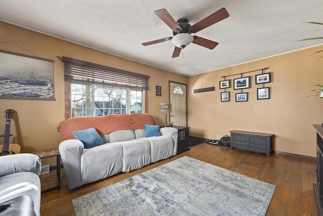 living room with dark wood-style floors, a ceiling fan, and baseboards