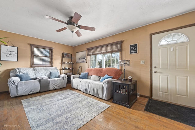 living room with ceiling fan, a textured ceiling, a healthy amount of sunlight, and light wood-style flooring