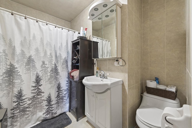 bathroom featuring toilet, a shower with shower curtain, tile walls, tile patterned flooring, and vanity