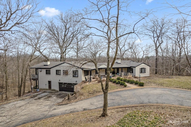 view of front of property with a garage, a chimney, and driveway