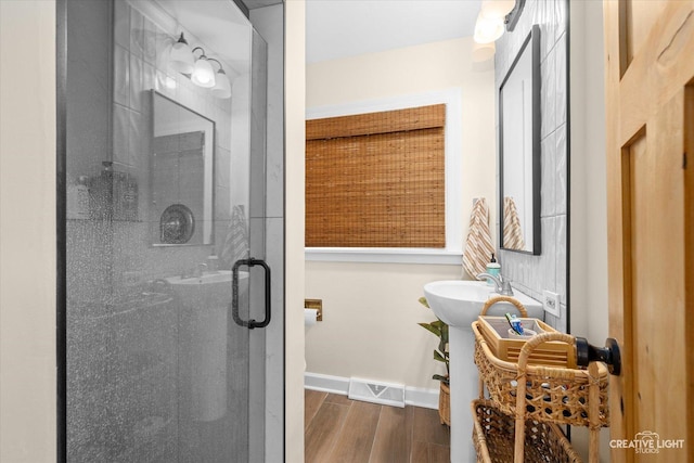 full bath with a stall shower, visible vents, baseboards, and wood finished floors