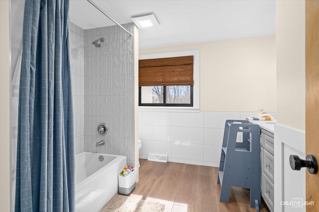 bathroom with visible vents, toilet, shower / tub combo with curtain, wood finished floors, and tile walls