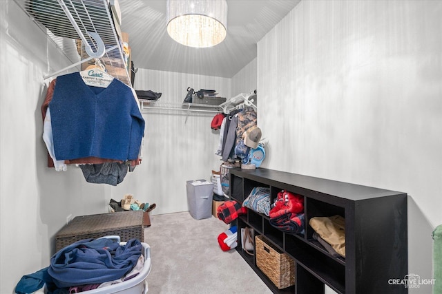 spacious closet with a chandelier and carpet flooring