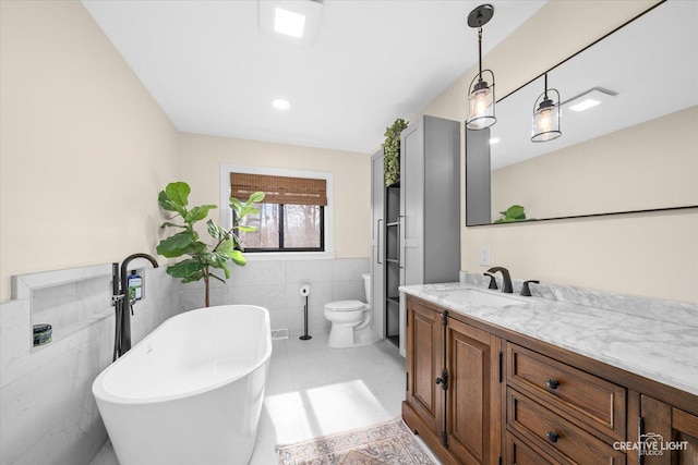 bathroom featuring vanity, a soaking tub, wainscoting, tile walls, and toilet