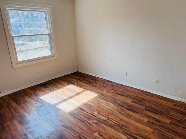 unfurnished room featuring baseboards and wood finished floors