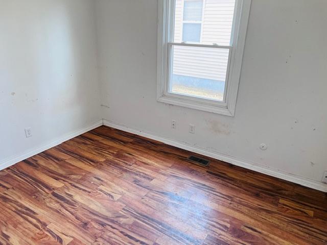 unfurnished room with visible vents, baseboards, and wood finished floors