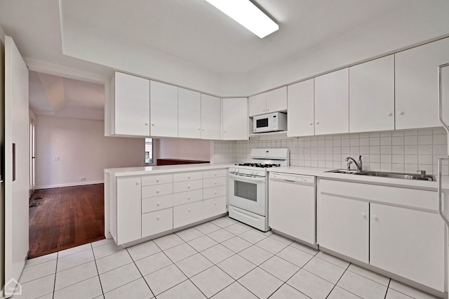 kitchen with tasteful backsplash, white appliances, light countertops, and a sink