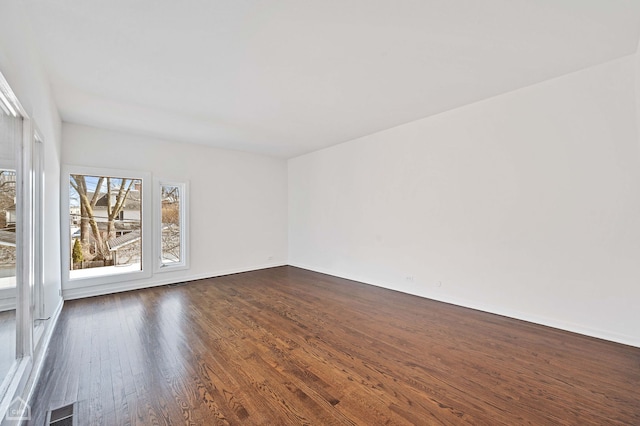 empty room featuring visible vents and dark wood-type flooring