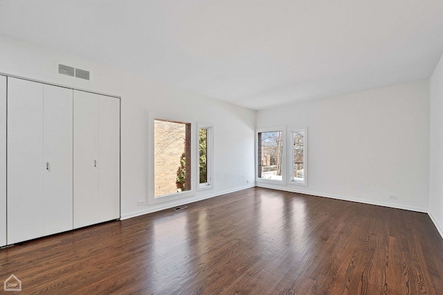 unfurnished bedroom featuring dark wood-style floors, visible vents, and baseboards