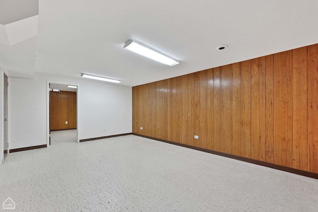 unfurnished room featuring baseboards and wooden walls