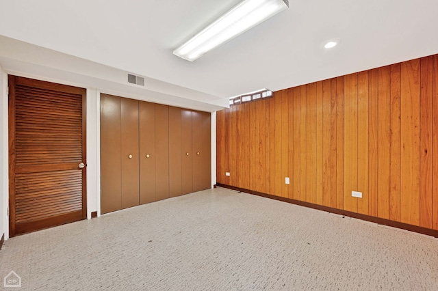 unfurnished bedroom with wooden walls, visible vents, and two closets