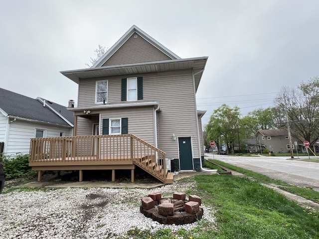 rear view of property featuring a wooden deck and a fire pit