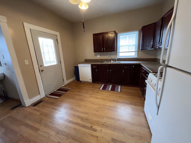 kitchen featuring white appliances, visible vents, light wood finished floors, a sink, and dark brown cabinetry